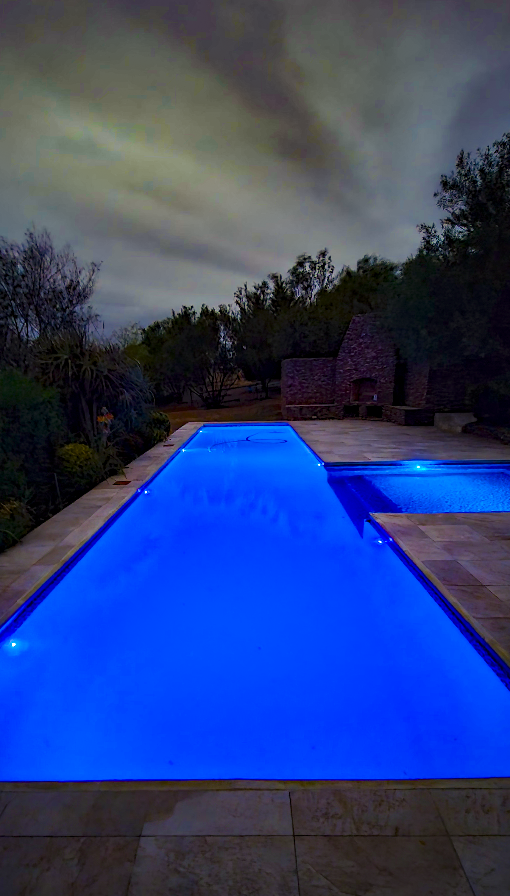 Exterior & Architecture Pool at night showing brilliant blue underwater lighting illuminating the swimming pool against dramatic evening sky
