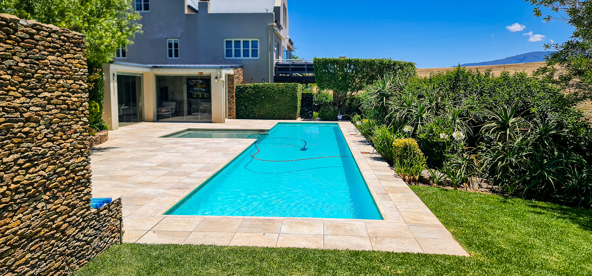 Exterior & Architecture Modern swimming pool area with stone walls and landscaping at Heritage Farm Estate