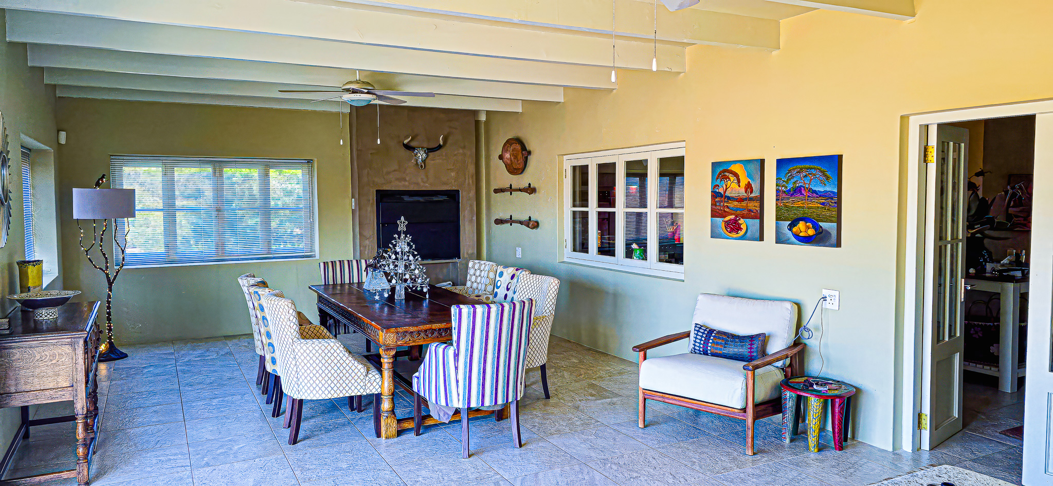 Interior Spaces Elegant dining room interior with exposed beam ceiling, refined furniture, colorful artwork, and fireplace