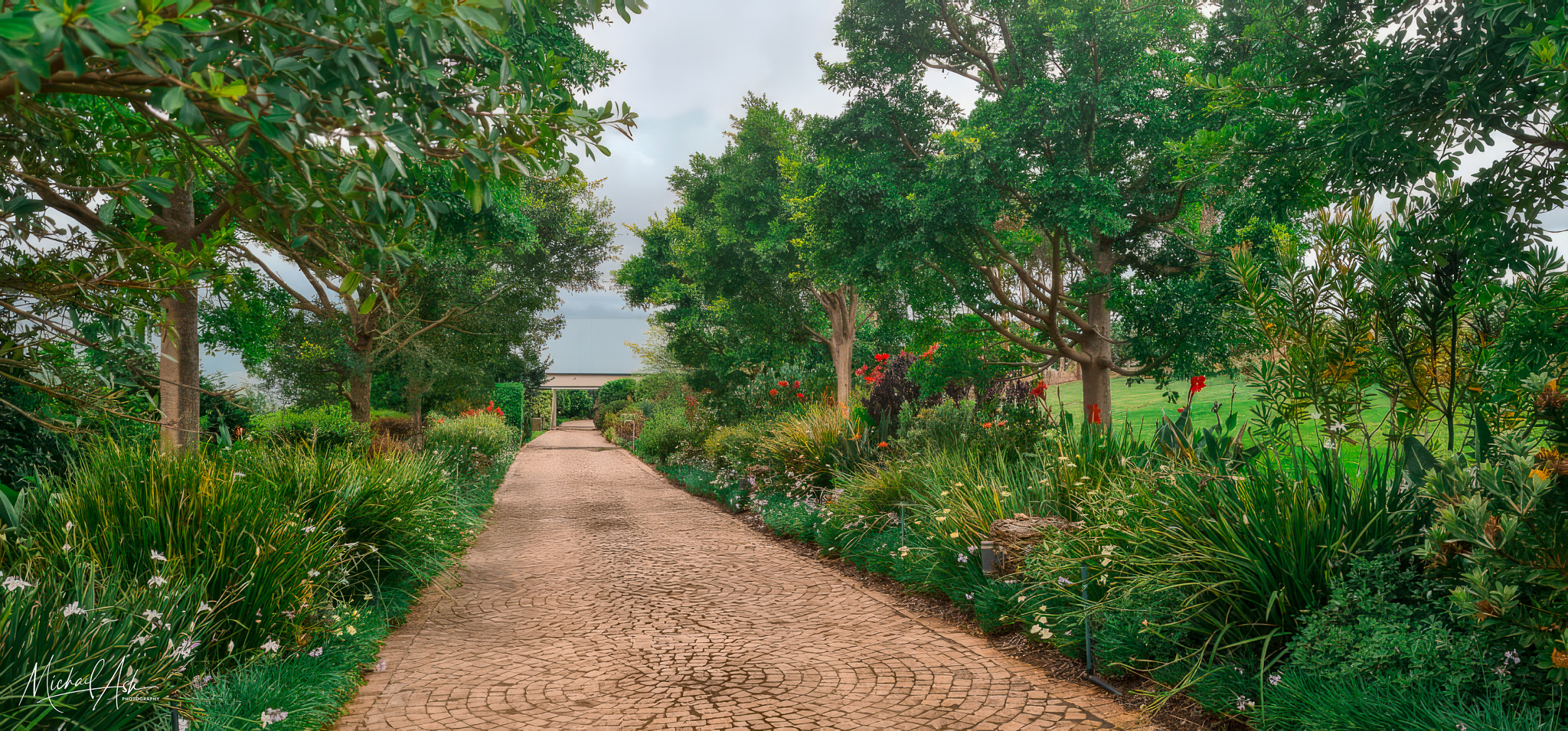 Gardens & Grounds Entrance garden showing circular brick pathway winding through mature landscaping with indigenous plants and trees