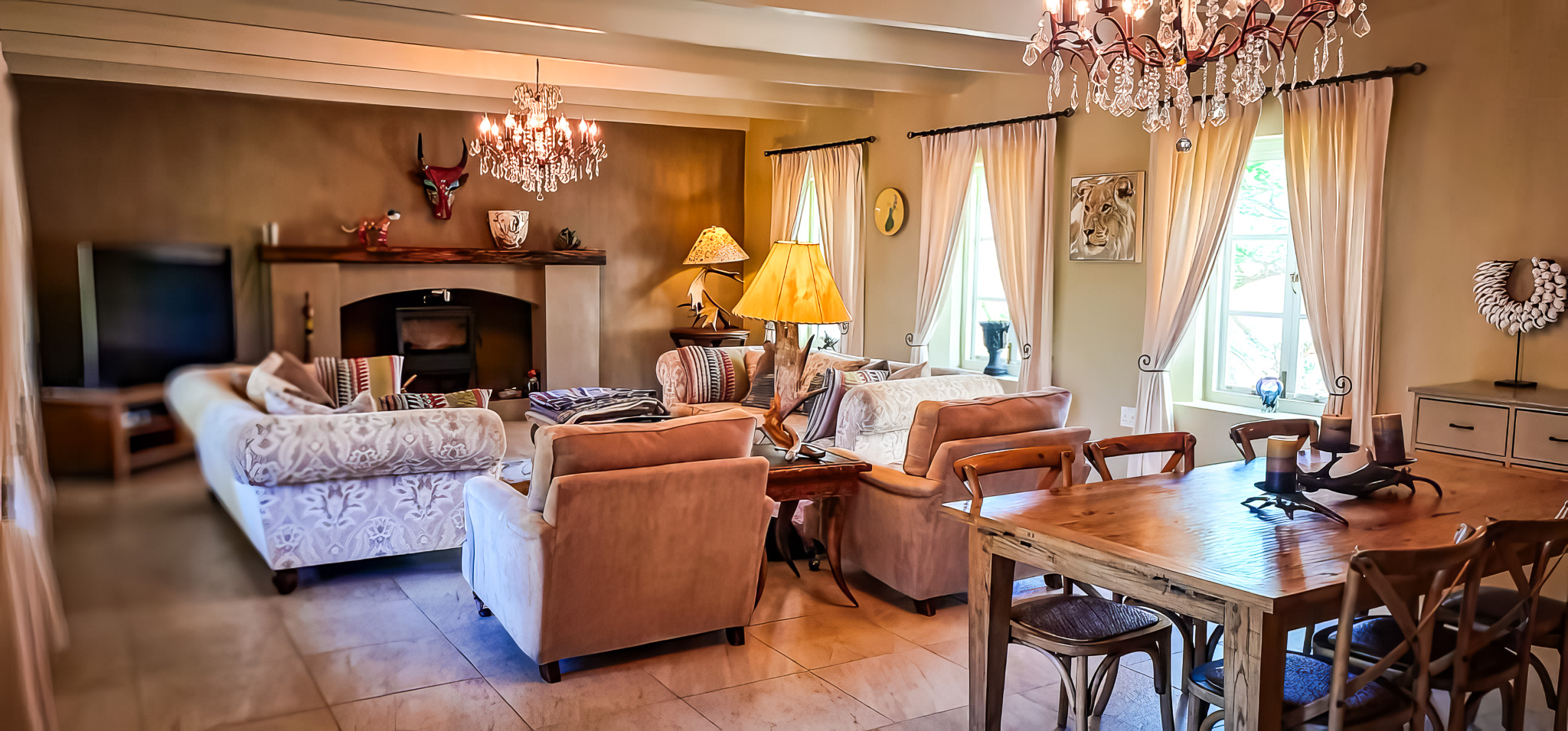 Interior Spaces Main lounge interior with exposed beam ceiling, crystal chandeliers, fireplace, comfortable seating, and wildlife artwork