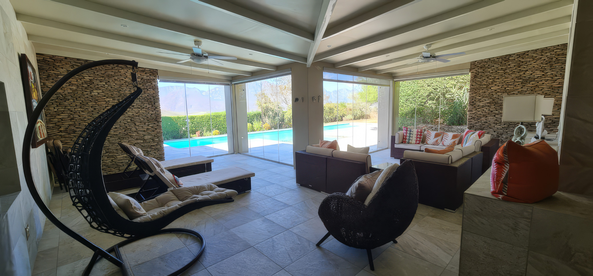 Interior Spaces Pool room interior with exposed beam ceiling, stone accent walls, glass doors to pool area, and modern seating